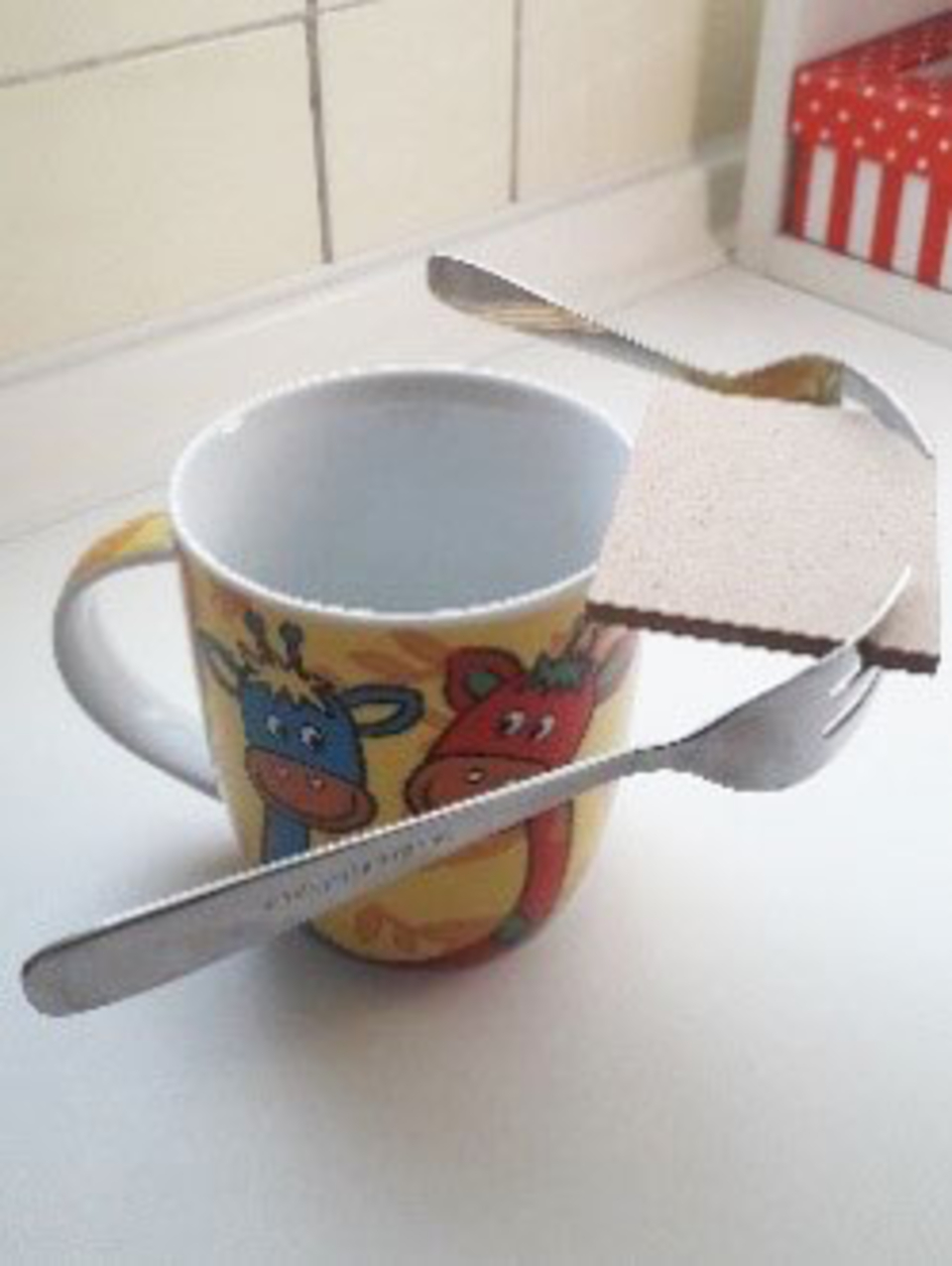 Das Bild zeigt einen bunten Becher mit Tiermotiven, in dem eine Gabel und ein Messer sowie ein Stück Holz platziert sind. Diese Anordnung könnte für ein Experiment zur Schwebetechnik oder zum Thema Auftrieb verwendet werden.
