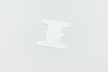 Das Bild zeigt eine weiße, flache Kunststoffschablone mit einer speziellen Form, die mehrere Aussparungen aufweist. Sie scheint für experimentelle oder kreative Aktivitäten im Bildungswesen konzipiert zu sein, möglicherweise als Teil eines Bausatzes oder zur Herstellung von Modellen.