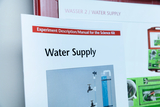 Das Bild zeigt eine Anleitung mit dem Titel „Water Supply“ für ein Experimentierset im Bildungsbereich. Zusätzlich sind Teile des Sets abgebildet, die vermutlich für Experimente zur Wasserversorgung verwendet werden.
