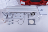 Das Bild zeigt eine Sammlung von Experimentiermaterialien, darunter verschiedene Halterungen, Rohre, eine Brenner, eine Glasblase und eine Plattform. Die Utensilien sind auf einem weißen Tisch angeordnet und bieten eine Grundlage für physikalische Experimente im Bildungswesen.