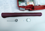 Das Bild zeigt eine Zusammenstellung von Experimentiermaterialien, darunter ein lila Stoff, ein metallischer Löffel, ein Zündholz und eine Teelichtkerze. Im Hintergrund sind Anweisungen für Experimente zur sicheren Handhabung von Feuer zu sehen.