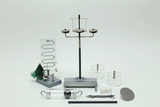Das Bild zeigt eine Sammlung von Experimentiermaterialien, darunter eine Wägebrücke, transparente Zylinder und verschiedene Gewichte. Diese Utensilien sind für den experimentellen Einsatz im Bildungsbereich konzipiert und ermöglichen praktische physikalische Untersuchungen.