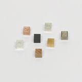 Das Bild zeigt eine Sammlung von Würfeln aus verschiedenen Materialien, die mit chemischen Symbolen geprägt sind. Diese Stoffe, darunter Aluminium (Al), Kupfer (Cu) und Zinn (Sn), dienen Bildungszwecken im Experimentierbereich.