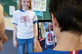 Ein Schüler steht mit einem interaktiven T-Shirt vor einem Tablet, das ein Augmented-Reality-Modell seines Körpers zeigt. Die Darstellung hebt die Rückenmuskulatur hervor, was die Verbindung zwischen Mode und Bildung verdeutlicht.