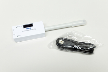 Ein kabelloses Messgerät für elektrische Leitfähigkeit ist abgebildet, das über ein digitales Display verfügt. Neben dem Gerät liegt ein USB-Kabel in einer Verpackung, um es mit Strom zu versorgen oder Daten zu übertragen.