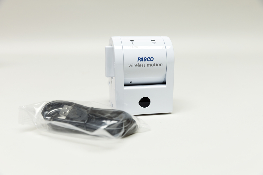 Ein Wireless Motion Sensor in Weiß ist abgebildet, der für Experimentierzwecke genutzt wird. Neben dem Sensor liegt ein USB-Kabel in Plastikfolie verpackt.