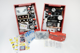 Das Schüler-Set Chemie III mit dem Thema Säuren, Laugen und Salze steht mit dem kompletten Lieferumfang auf dem Tisch. Man kann in die beiden Exeperimentierwannen schauen und vor den Wanne liegen noch die beiden Einräumpläne, die Aufkleber, sowie Schutzbrillen und eine Taschentücherbox auf dem Tisch.